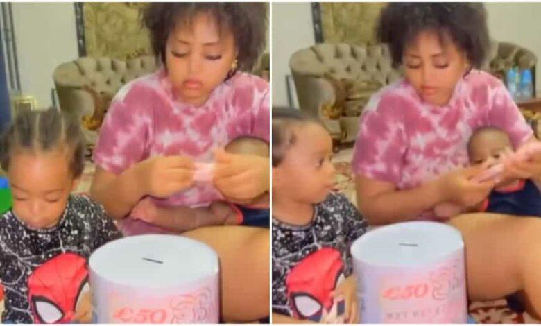 Backlashes trail video of Regina Daniels and sons putting wraps of money in piggy bank